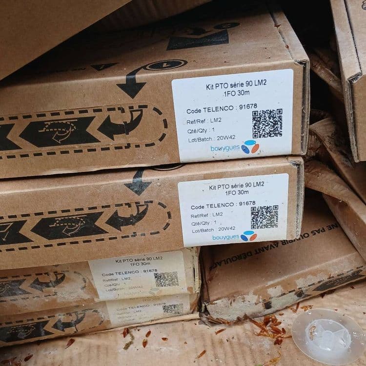 Voici une estimation des déchets présents sur les lieux, basée sur l'image fournie :

*   **Carton d'emballage** : Il y a une quantité importante de cartons d'emballage, dont plusieurs provenant de kits fibre optique (série 90 LM2 1FO 30m et PTO BM3 1FO 60m Box). On peut estimer le poids total du carton à environ 5-7 kg, compte tenu du volume et de l'épaisseur visible. La quantité de cartons est d'environ une vingtaine.

*   **Bobine de câble** : On distingue une bobine de câble blanc, probablement du câble de fibre optique. Son poids est estimé à environ 1-2 kg. La quantité est de 1 bobine.

*   **Câble de fibre optique** : Il y a également une quantité de câble de fibre optique déroulé. On peut estimer le poids à environ 1-2 kg. La quantité est de 1 faisceaux.

*   **Emballages divers** : De plus petites quantités d'emballages et de protections diverses en carton sont visibles. On peut estimer leur poids combiné à environ 0.5 - 1 kg. La quantité d'emballages divers peut être estimée à environ 5-10 pièces.
